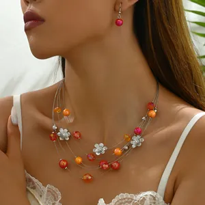 Detail of multi-strand beaded flower necklace set with red and orange gems on model