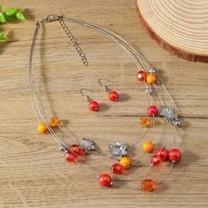 Detail of multi-strand floral necklace set with colorful beads on wooden background