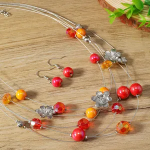 Detail of bohemian multilayer necklace and earrings set with red and orange floral beads
