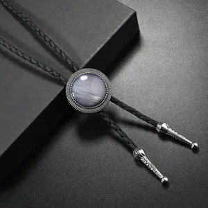 Détail du bolo tie montrant les embouts ciselés en argent et le cordon tressé noir