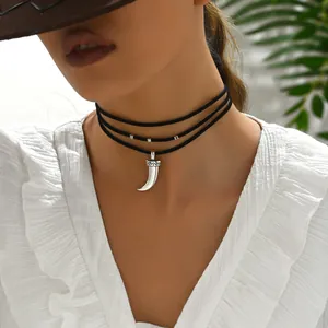 Détail du ras-du-cou en velours noir à trois rangs avec pendentif corne et motifs gravés