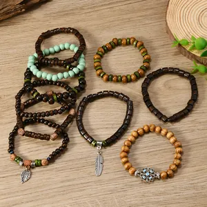 Detail of bohemian wood bead bracelets with metallic leaf and feather charms on a wood surface