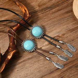 Detail einer Boho-Bolo-Krawatte mit Türkis-Sonnenblume und silbernen Feder-Anhängern