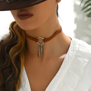 Détail d'un choker bohème avec plumes argentées et perle turquoise sur daim marron