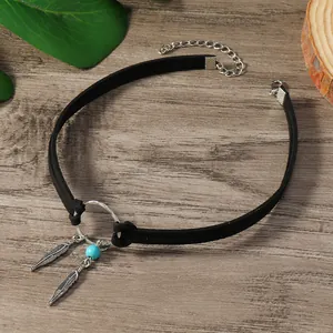 Détail d'un choker bohème noir avec pendentifs plumes argentées et perle turquoise