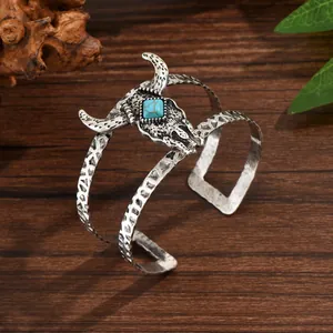 Détail macro du bracelet manchette rétro avec tête de taureau et turquoise sur bois