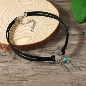 Détails du choker bohème avec plumes en argent et perle turquoise sur fond de bois
