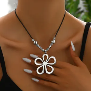 Gros plan d'un pendentif fleur argentée avec perles métalliques vintage sur cordon noir