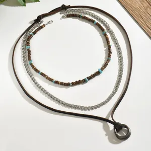 Detail of bohemian layered necklace with turquoise beads, silver chain, and leather pendant