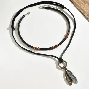 Macro detail of bohemian layered necklace with bronze feather pendants and ethnic beads