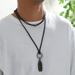 Detail of layered men's necklace with leather rope, wooden beads and feather pendants