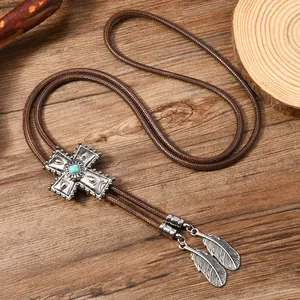 Nahaufnahme der Vintage-Bolo-Krawatte mit Türkis-Kreuz-Anhänger und silbernen Federn