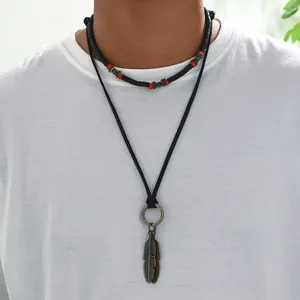 Detail of men's layered necklace featuring colorful beads and twin metal feather charms