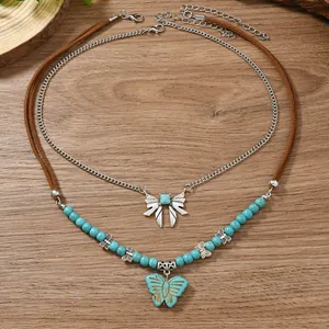 Collier double couche bohème avec pendentif papillon, perles turquoise et cordon brun