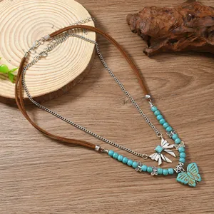 Détail du collier bohème papillon avec perles turquoise et cordon en velours marron