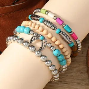 Detalle de pulseras bohemias multicapa con cuentas turquesas y un colgante de luna