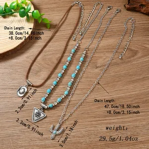 Detail of Western-style layered necklaces with cactus and cowboy hat charms on wood background