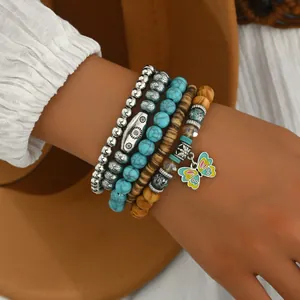 Detalle de pulseras boho con cuentas turquesas y colgante de mariposa colorido