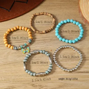 Detalle de cinco pulseras elásticas bohemias con cuentas turquesas y colgante de mariposa