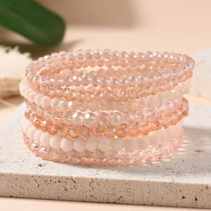 Set of five beaded elastic bracelets with peach and champagne crystals on travertine