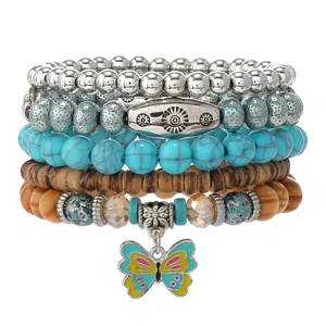 Detalle de pulsera bohemia multicapa con cuentas de turquesa y colgante de mariposa esmaltada