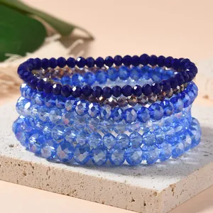 Stackable elastic bracelets set with multifaceted blue crystal beads on stone display