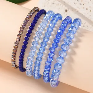 Close-up of six stacked stretch bracelets featuring faceted blue crystal glass beads