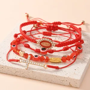 Dettaglio del set di 4 braccialetti rossi intrecciati con perline, malocchio e croce