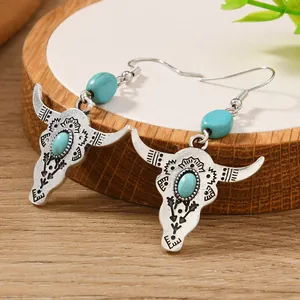 Detailed shot of bohemian bull skull earrings with turquoise stones on a wooden stand