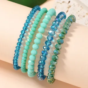 Macro detail of multi-layer faceted teal crystal bead bracelets on a pink display