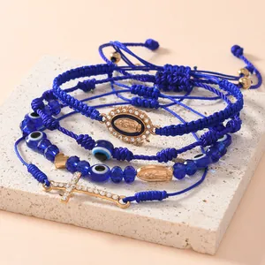 Dettaglio bracciali blu intrecciati con medaglia Maria Vergine e ciondolo a croce