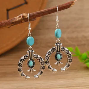 Detail of bohemian silver alloy earrings with turquoise beads hanging on a dry branch