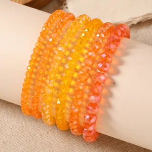 Detail of six warm gradient crystal stretch bracelets with faceted beads on a display roll
