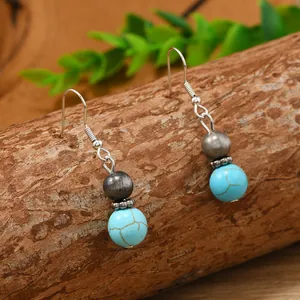 Detail of bohemian drop earrings with turquoise beads and rustic silver charms on wood