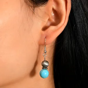 Close-up of bohemian drop earring featuring textured silver beads and turquoise stone