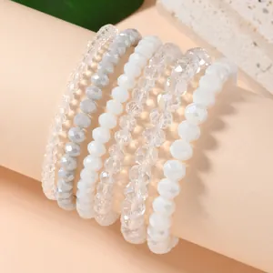 Detail of seven stacked faceted crystal stretch bracelets in clear, opal, and grey tones