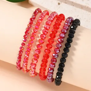 Macro detail of six layered elastic beaded bracelets with faceted red and black crystals