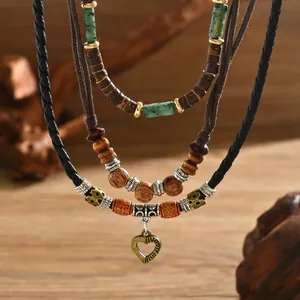 Détail d'un collier bohème à plusieurs rangs avec perles en bois et cœur en bronze