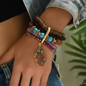 Detail of bohemian layered beaded bracelet featuring multi-color stones and a teardrop pendant