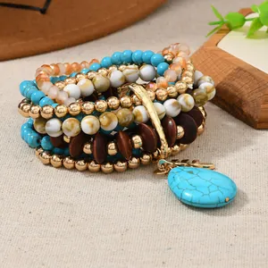 Detail of bohemian multilayer bracelet with turquoise beads and wood charms on beige fabric