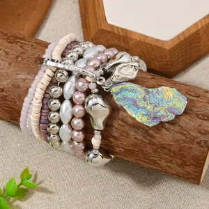 Detail of bohemian multilayer beaded bracelets with a large crystal pendant on wood