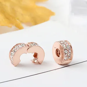 Macro shot of rose gold charm clips with pave crystal setting and opening mechanism