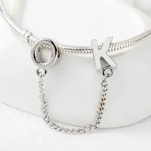 Dettaglio del bracciale a maglia serpente argento con ciondoli a lettera O e K lucidi