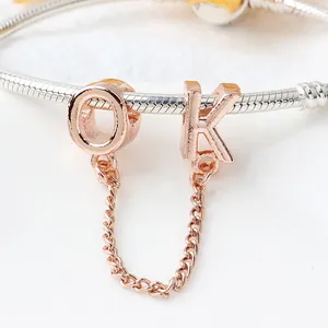 Dettaglio macro del ciondolo con lettere OK oro rosa su bracciale a catena serpente argento