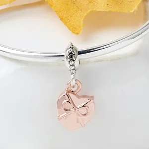 Colgante de corazón en oro rosa con detalle de lazo sobre pulsera para mujer