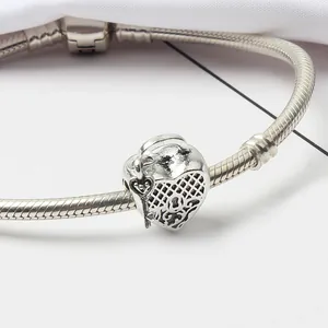 Detalle macro de dije de corazón plateado con colgante de llave en pulsera de serpiente