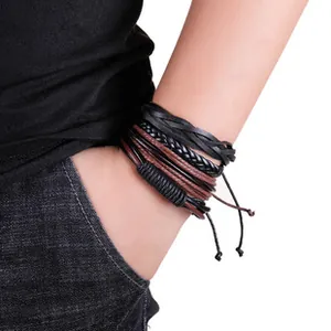 Dettaglio di bracciali multistrato in pelle intrecciata nera e marrone su un polso