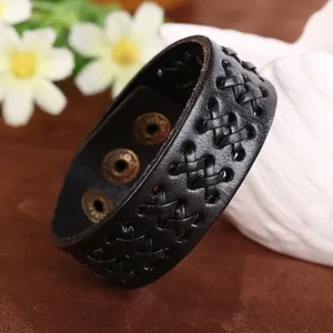 Dettaglio del bracciale in pelle nera intrecciata con bottoni a pressione in bronzo