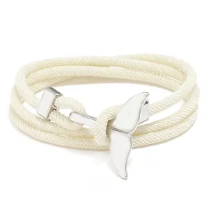 Détail d'un bracelet en corde tressée crème avec un fermoir en métal en forme de baleine