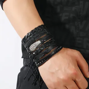 Detail von mehrlagigen Lederarmbändern mit Metallfeder-Anhängern am Herrenhandgelenk